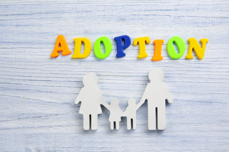 Word ADOPTION and figure in shape of family on light wooden backgroundの写真素材