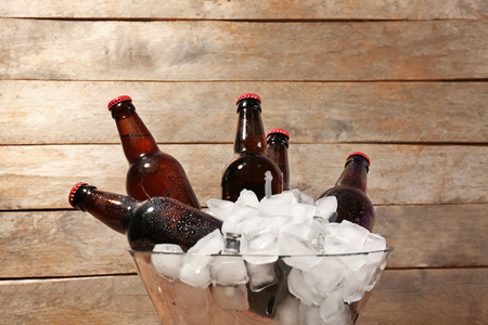 Bowl with bottles of beer in ice on wooden backgroundの写真素材