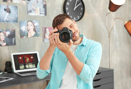 Young photographer with camera in office
