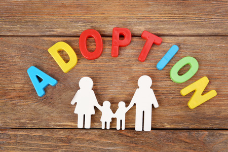 Word ADOPTION and figure in shape of happy family on wooden backgroundの写真素材