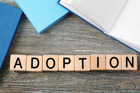 Cubes with word ADOPTION and notepads on wooden background
