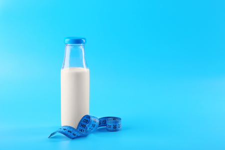 Bottle of milk with centimeter on blue backgroundの写真素材