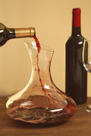 Pouring wine in carafe on wooden tableの写真素材