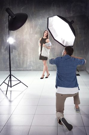 Young beautiful model posing for professional photographer in studioの写真素材