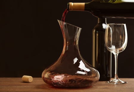 Pouring wine in carafe on wooden tableの写真素材
