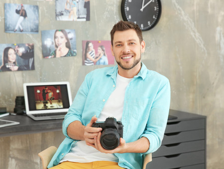 Young photographer with camera in office