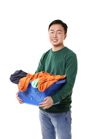 Happy Asian man holding plastic box with clothes on white backgroundの写真素材