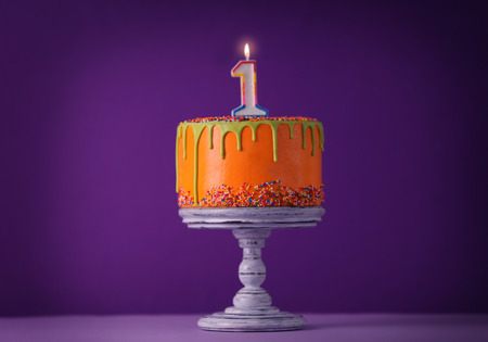 Birthday cake with one candle on purple background