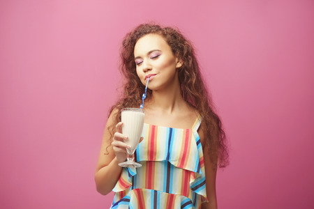 Young beautiful woman with milk shake on color background