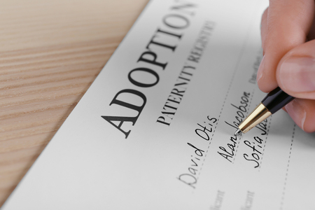 Female hand filling in adoption paternity registry at tableの写真素材