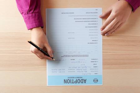 Female hands filling in adoption paternity registry at tableの写真素材