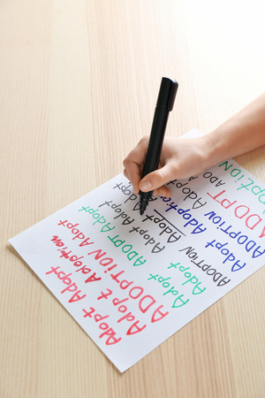 Female hand writing word "Adoption"の写真素材