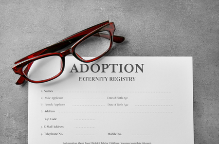 Glasses and adoption blank on tableの写真素材