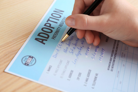Female hand filling in adoption paternity registry at tableの写真素材