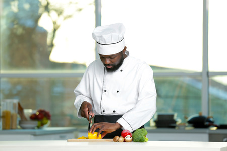 African American chef cutting vegetables in kitchenの写真素材