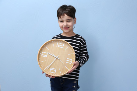 Cute little boy with big clock on color backgroundの写真素材