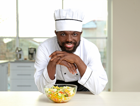 African American chef with tasty salad in kitchen