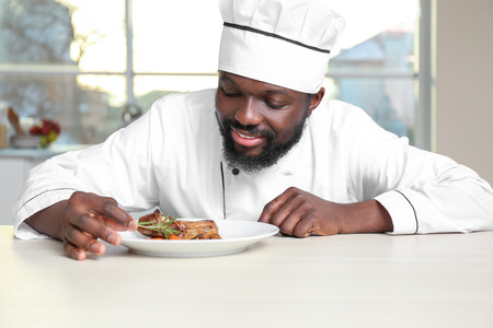 African American chef cooking tasty meat in kitchenの写真素材