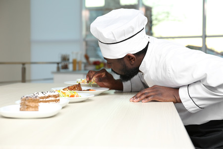 African American chef adding rosemary to tasty dish in kitchenの写真素材
