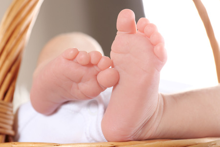 Feet of cute little baby lying in wicker basket, closeupの写真素材