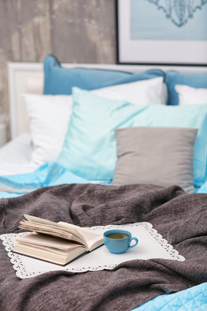 Cup of hot drink and book on bedの写真素材