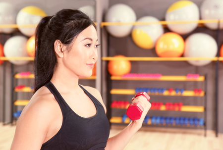 Sporty woman training with dumbbell in gymの写真素材