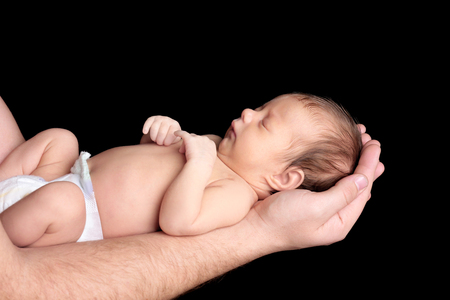 Father with cute sleeping baby on black background