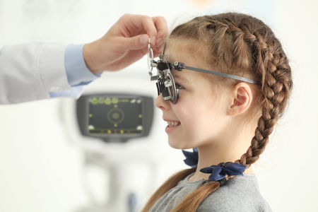 Ophthalmologist examining eyes of little girl in clinicの写真素材