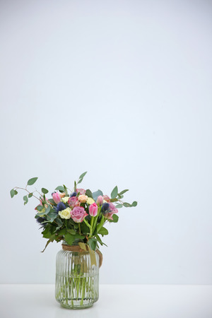 Glass vase with beautiful bouquet on light backgroundの写真素材