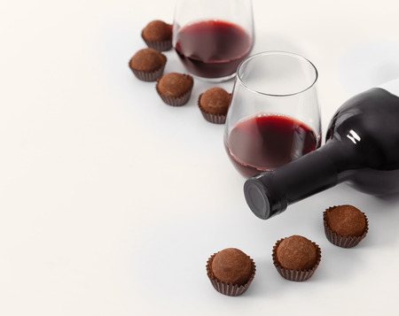 Delicious chocolate truffles and red wine on white backgroundの写真素材