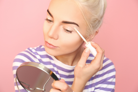 Beautiful young woman applying concealer on eyelidの写真素材