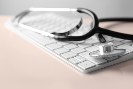 Modern wireless keyboard and stethoscope on white background