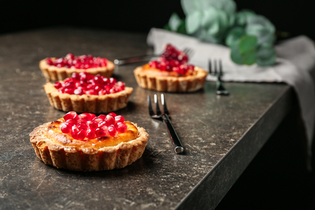 Tasty tarts with fresh seeds of pomegranates on gray tableの写真素材