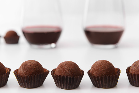 Delicious chocolate truffles and red wine on white backgroundの写真素材