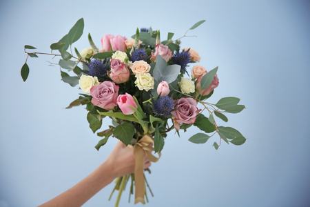 Female hand holding beautiful bouquet on color backgroundの写真素材