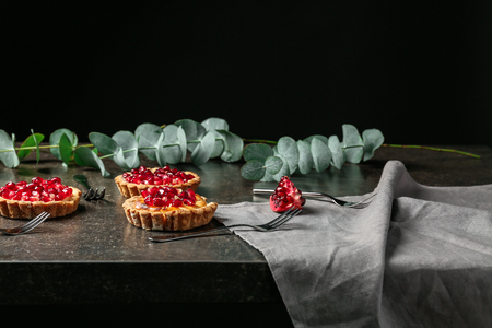 Tasty tarts with fresh seeds of pomegranates on gray tableの写真素材