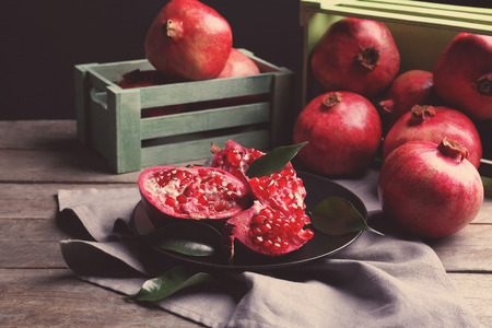 Composition of plate and wooden boxes with pomegranates on tableの写真素材