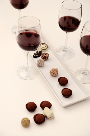 Delicious chocolates and glasses of wine on white tableの写真素材