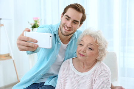 Young man taking selfie with grandmother at homeの写真素材
