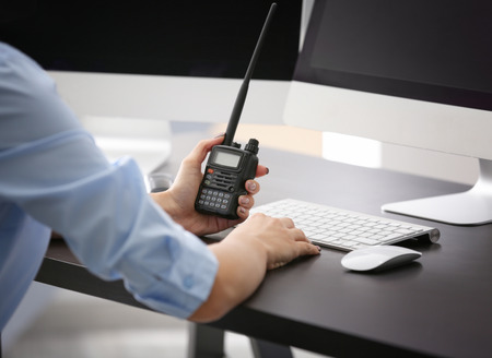 Female security guard holding portable radio in hand at workplaceの写真素材
