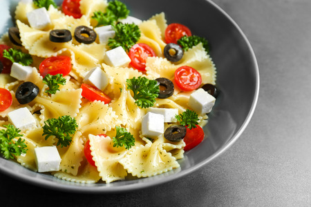 Pasta salad with tomatoes and cheese on tableの写真素材