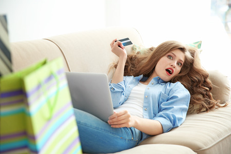 Beautiful young woman doing online shopping at homeの写真素材