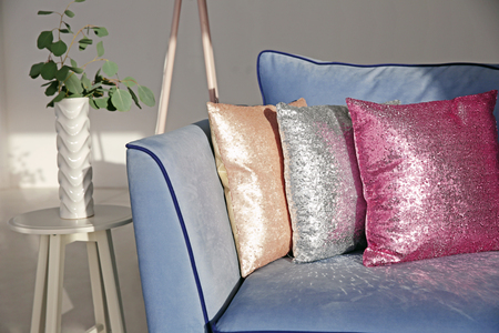 Three shiny decorative pillows on cozy sofa