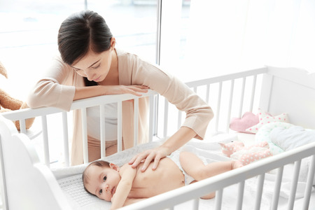 Happy mother with cute little baby lying in bedの写真素材