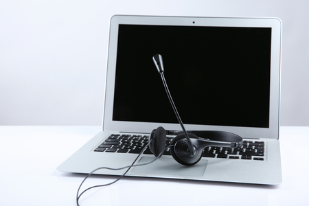 Laptop with headset on white tableの写真素材