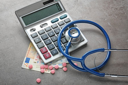 Calculator, pills, stethoscope and money on grey textured backgroundの写真素材