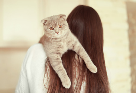Beautiful young woman with cute cat resting at homeの写真素材