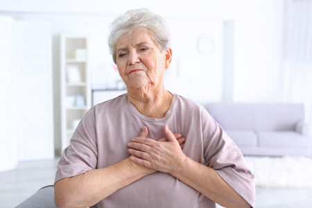 Elderly woman having heart attack at homeの写真素材