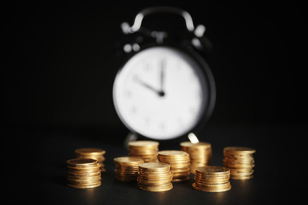 Stack of coins and alarm clock on backgroundの写真素材