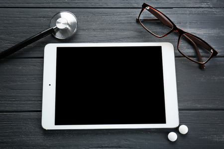 Tablet with eyeglasses on wooden backgroundの写真素材